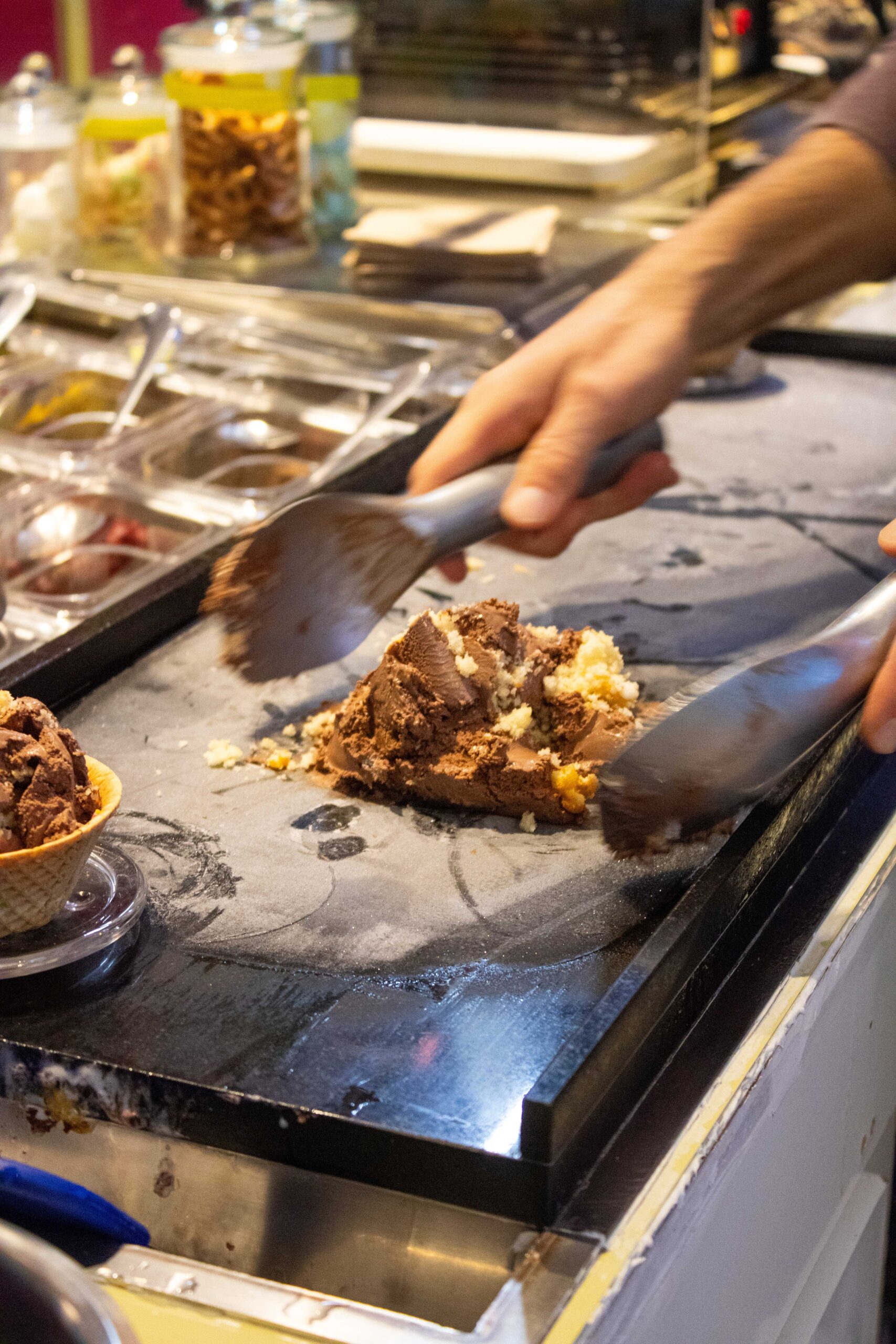 Eismischen Hier zu sehen wie ein Mitarbeiter das Eis mit Toppings auf dem Coldstone mischt